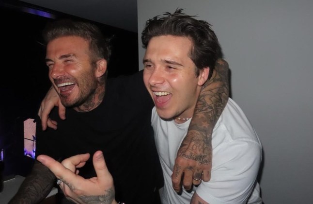 David and Brooklyn Beckham with their arms around one another's shoulders smiling