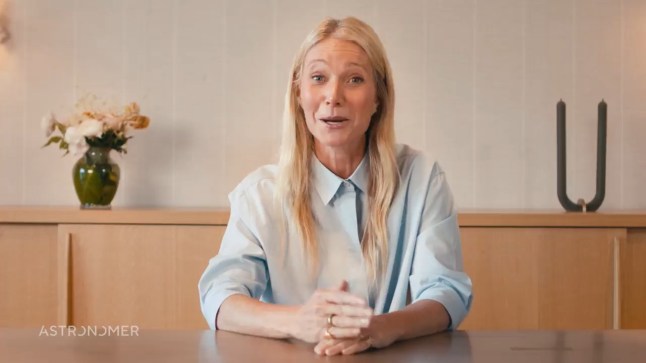 Gwyneth Paltrow sits at a desk in a conference room in a blue shirt in a video campaign as Astronomer's new 'very temporary' spokesperson