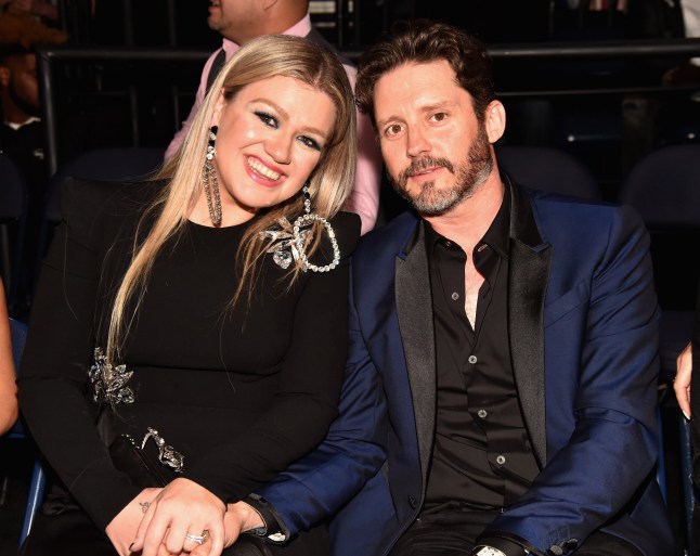 Kelly Clarkson and Brandon Blackstock smiling sat next to each other at an event in 2018