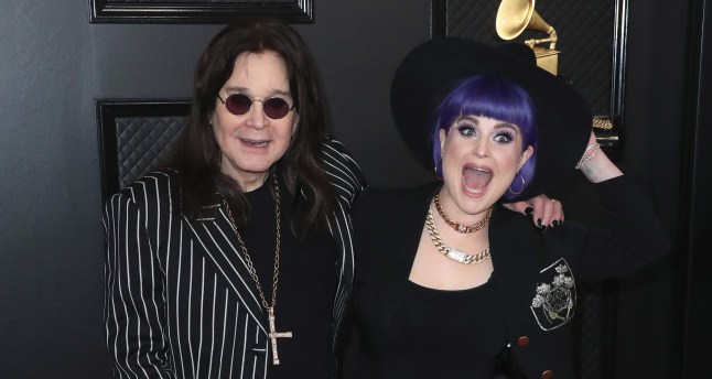Ozzy Osbourne in s pinstripe black suit and daughter Kelly Osbourne with purple hair and in a black hat pose together at the Grammy Awards in 2020