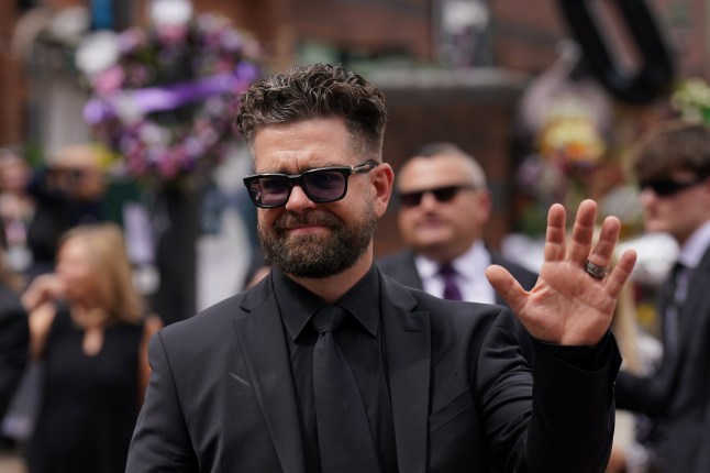Jack Osbourne waves to the crowd after viewing the messages and floral tributes left at the Black Sabbath Bridge bench on Broad Street in Birmingham in memory of Black Sabbath frontman Ozzy Osbourne, as his body is brought back to his home city for a procession following his death last week aged 76. Picture date: Wednesday July 30, 2025. Photo credit should read: Joe Giddens/PA Wire