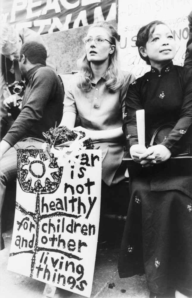 (Original Caption) LONDON: Actress Vanessa Redgrave (wearing glasses) sits on speakers' stand May 9th during an anti-war protest rally in Trafalgar Square. Next to Miss Redgrave is Madame Linh Qui, from Hanoi, who spoke at the rally. The actress holds a small bouquet which she intended to place at the foot of the Roosevelt Statue in Grosvenor Square, site of the American Embassy there, to honor the students killed during recent strife on Kent State University campus in Kent, Ohio.
